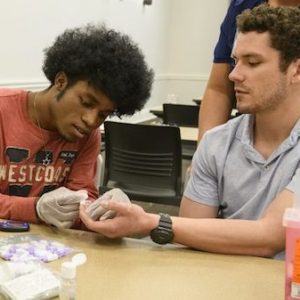 Micah Walls (left) and Conner Ball practice taking each other’s blood glucose levels. Photo by Thomas Graning/Ole Miss Communications