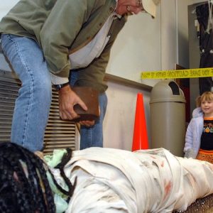 An Oxford Elementary School student lies on a bed of nails as a volunteer places a weight on her while other Spooky Physics Night participants observe. Photo by Nathan Latil