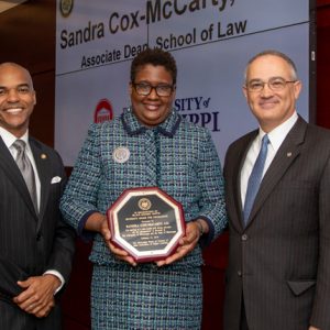 Dr. Steven Cunningham (left), chair of the IHL Diversity Committee, and UM Interim Chancellor Larry Sparks (right) congratualte Sandra Cox-McCarty on winning one of hte board’s Excellence in Diversity Awards.