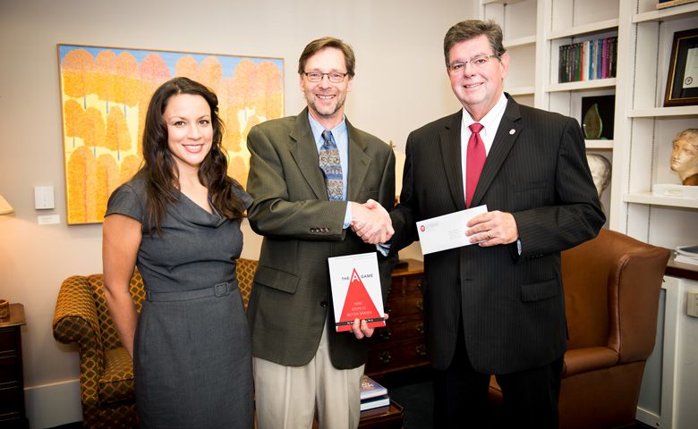 Ken Sufka (center), UM professor of psychology and pharmacology, and wife, Stevi, have established a scholarship from royalties received from the publication of Sufka's book. UM Provost Morris Stocks (right) was instrumental in making the book required reading for all entering students.