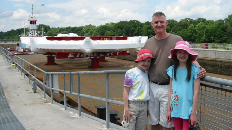 Breese Quinn and his son, Aidan, and daughter, Erin, watch the Muon g-2 ring pass through the G.V. ‘Sonny’ Montgomery Lock on the Tennessee-Tombigbee Waterway on July 15, 2013. Quinn is among the collaborators on a landmark experiment using the massive electromagnet at Fermilab. Photo courtesy Breese Quinn
