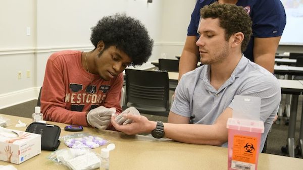 Micah Walls (left) and Conner Ball practice taking each other’s blood glucose levels. Photo by Thomas Graning/Ole Miss Communications